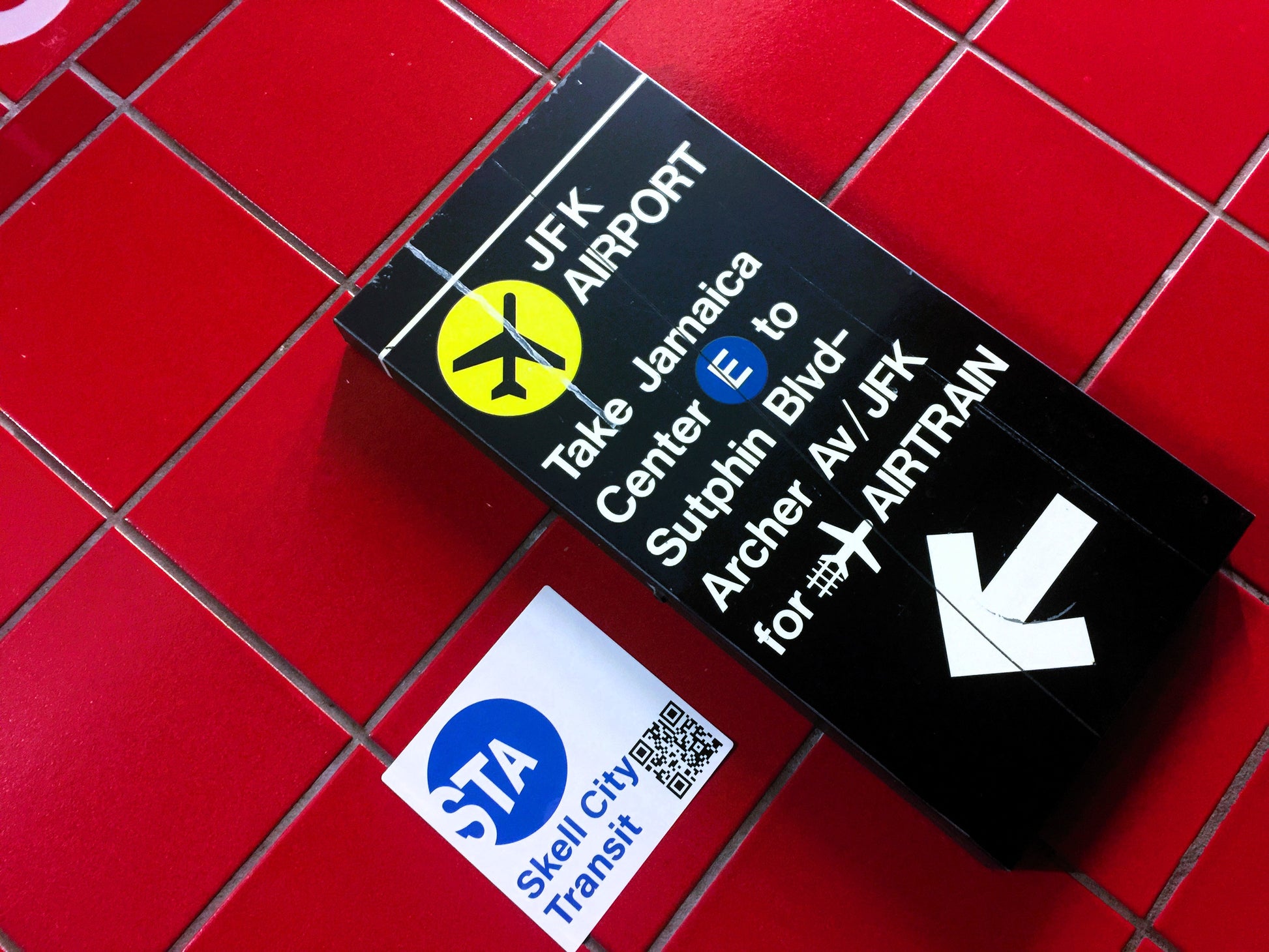 mta subway station sticker, from skell city posted next to Jamaica Center JFK airport sign.