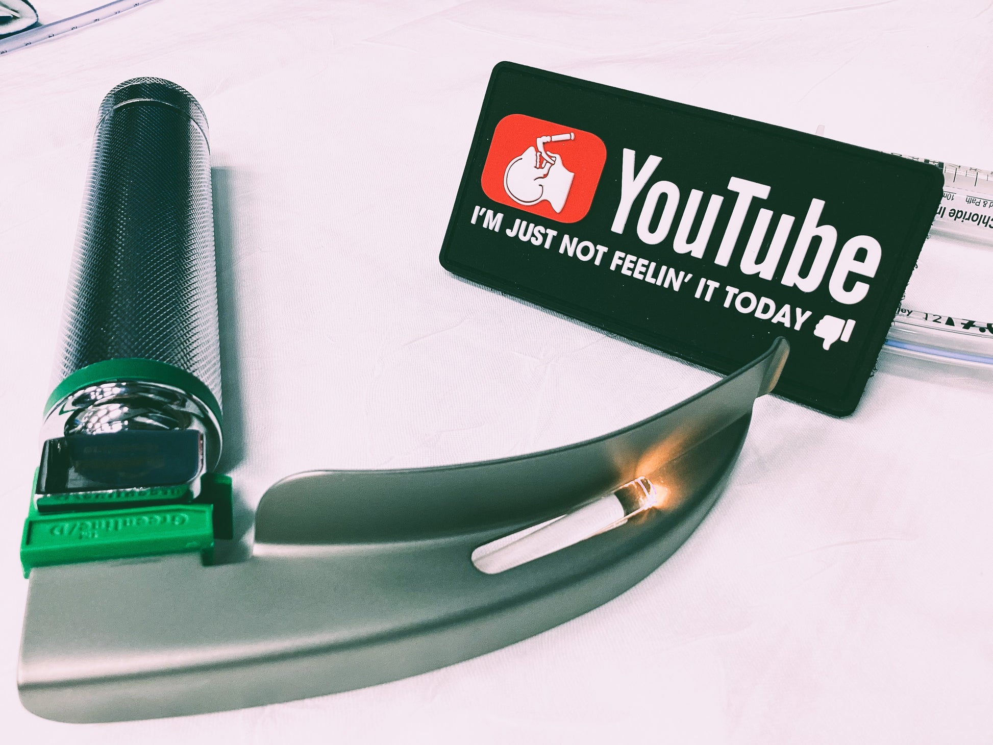 A close up view of skell city's PVC Velcro YouTube patch, with a laryngoscope blade and handle.