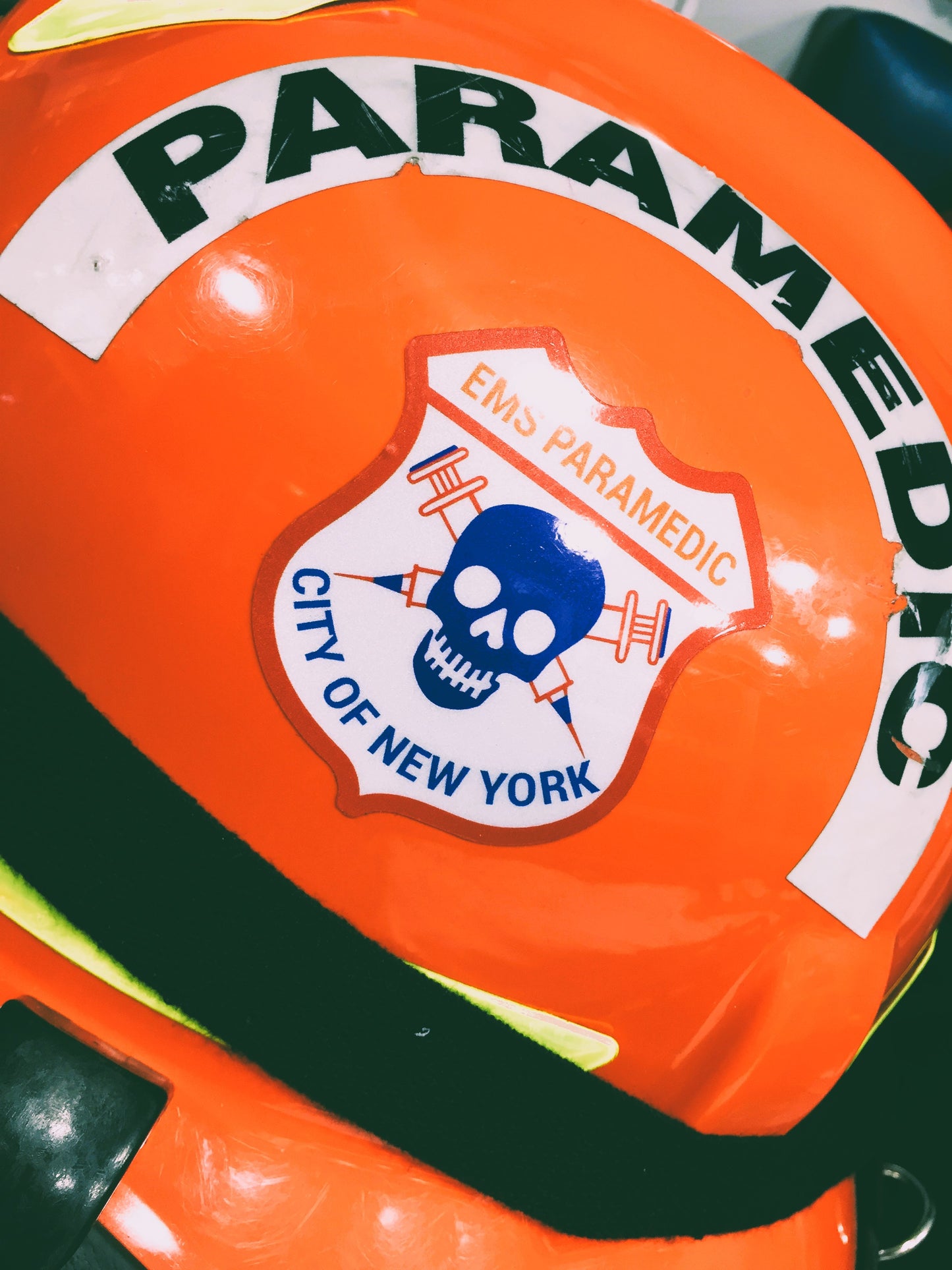 NYC skell city EMS Paramedic patch reflective sticker on the side of an orange ems bunker gear helmet.