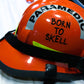 Born to Skell clear sticker applied to the side of an orange ems bunker gear helmet