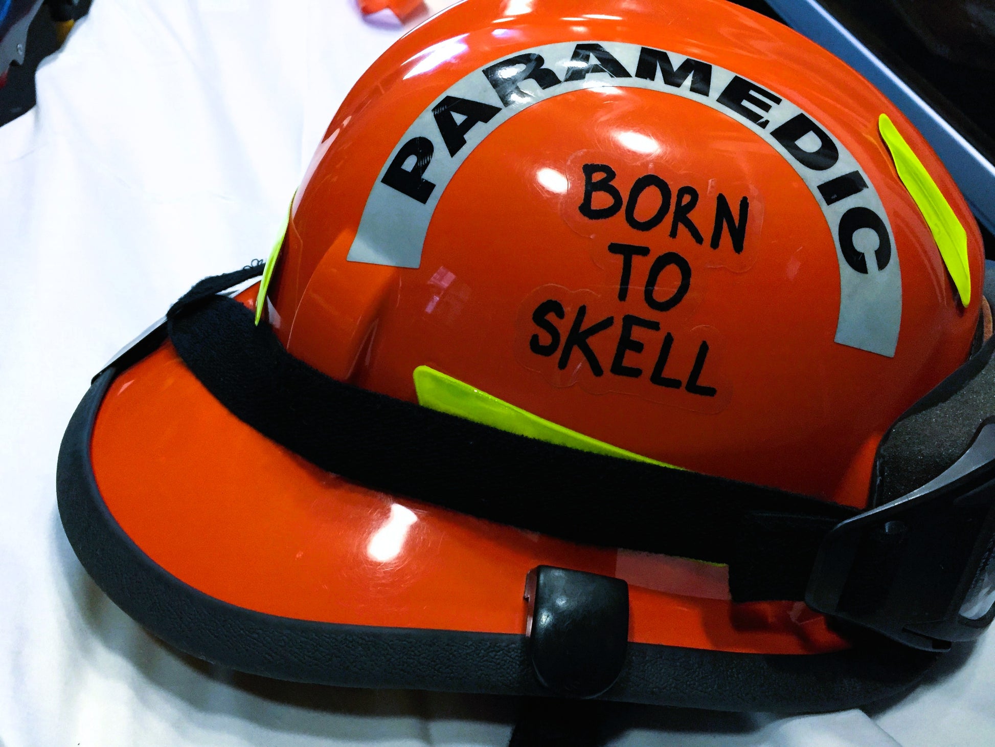 Born to Skell clear sticker applied to the side of an orange ems bunker gear helmet