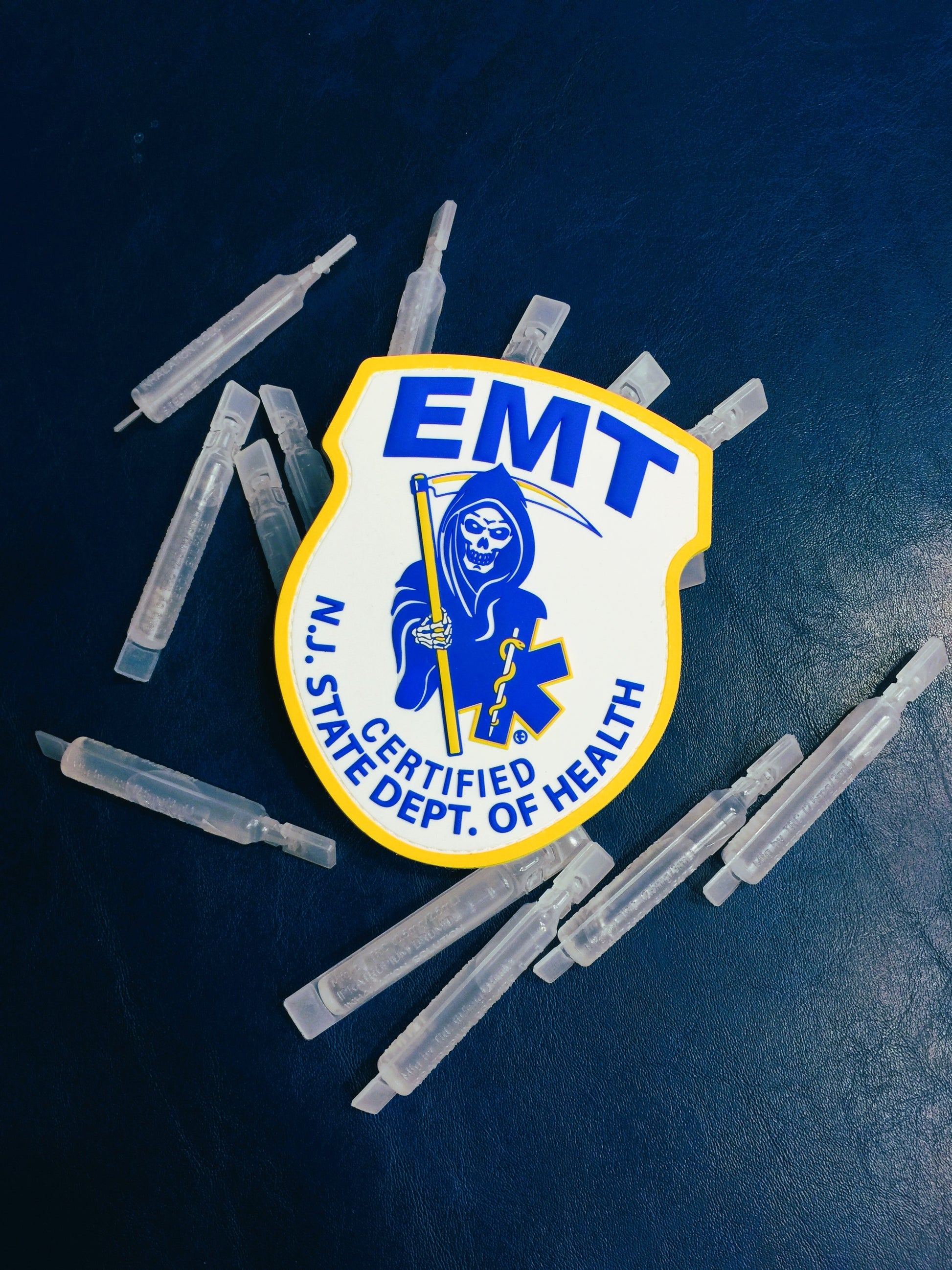 New Jersey EMT PVC Velcro Patch on top of plastic albuterol vials, up against a Blue leather background.