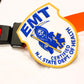 NJ EMT patch, from skell city, leaning up against orange stretcher strap buckle.