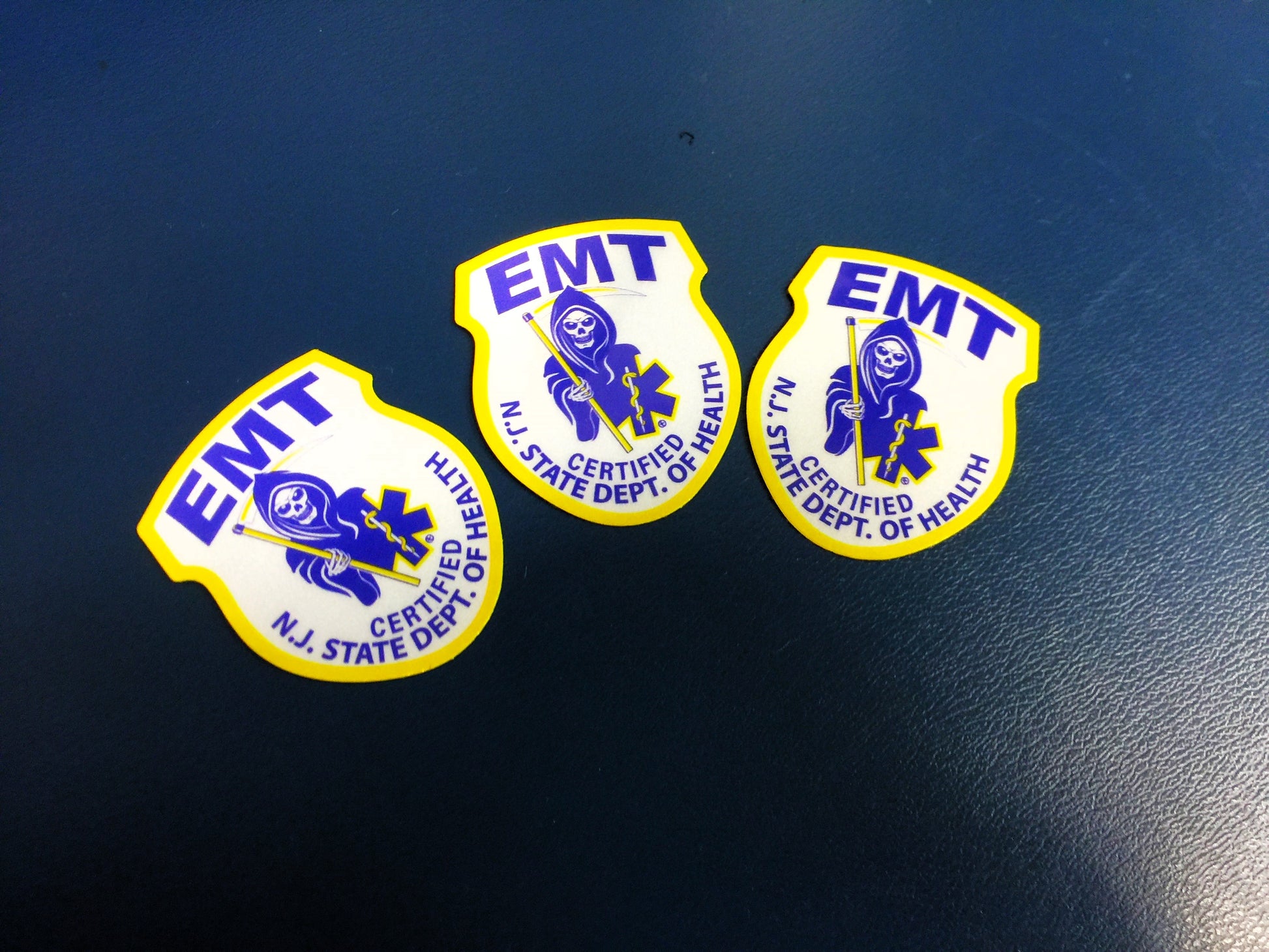 New Jersey EMT Patch from skell city Reflective Helmet Stickers against Blue leather ambulance bench background. 