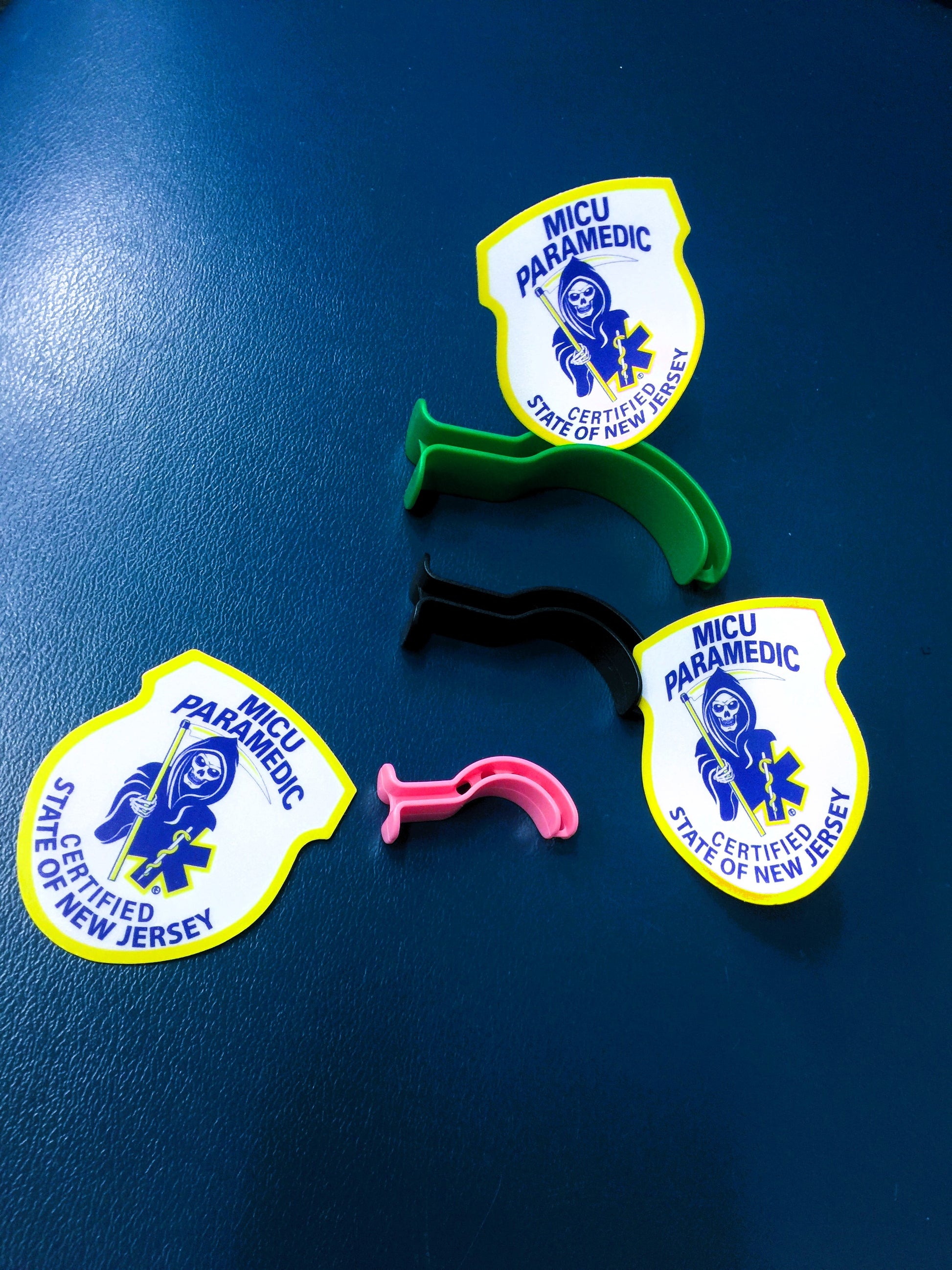 New Jersey MICU Paramedic Patch reflective stickers spread out around pediatric orophangeal airways against a blue leather background.