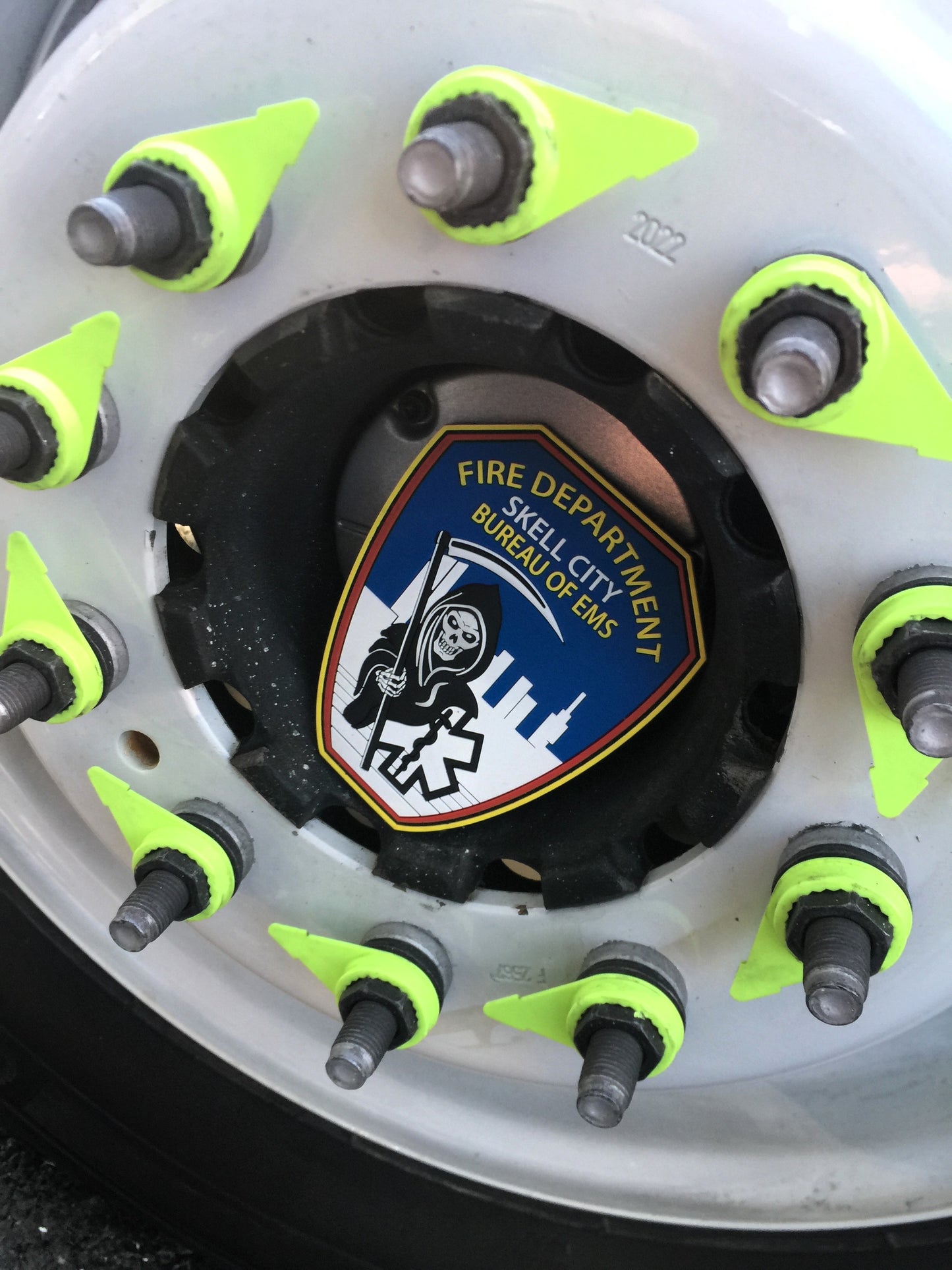 skell city EMS patch sitting inside of the spoke of an FDNY ambulance wheel. 