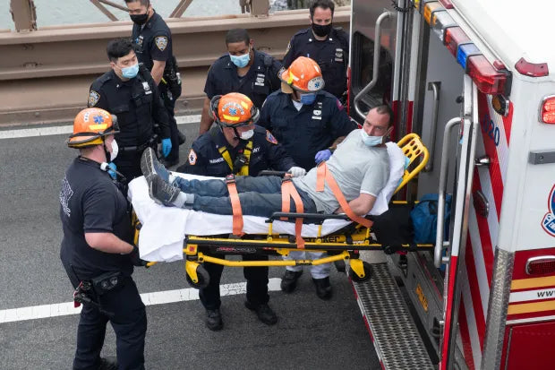 Skell lying on stretcher, handcuffed being loaded into back of FDNY ambulance.