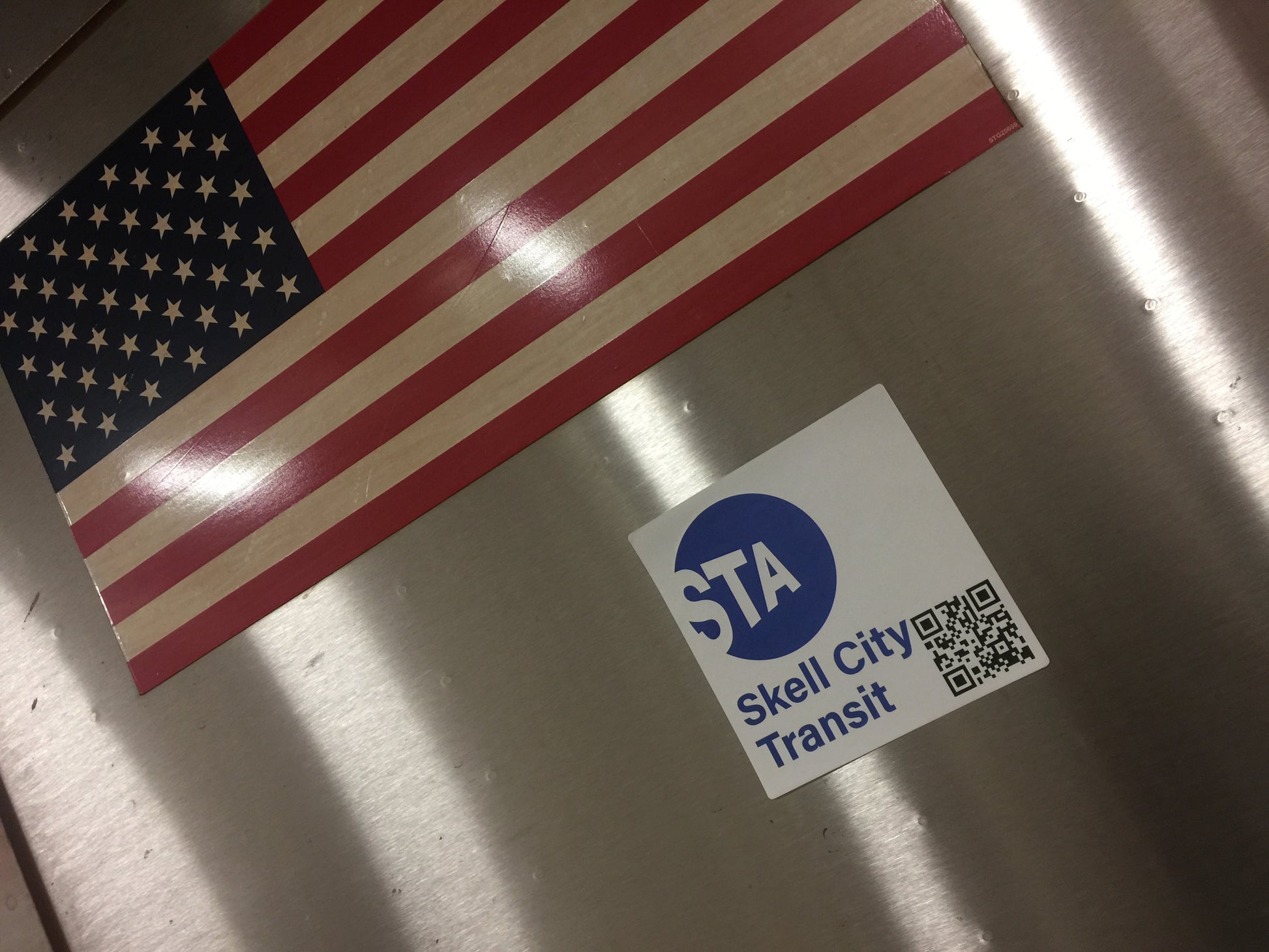 MTA station sticker, from skell city attached to the side of subway car next to the American Flag.